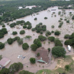 Houses and cars are partially submerged in flood waters in an aerial view near Kerrville